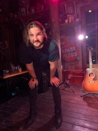 a man posing in front of an acoustic guitar